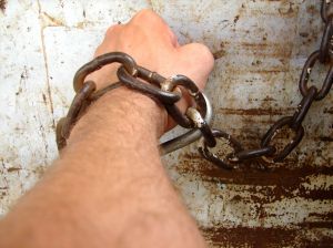 arm shackled to a wall with large chain