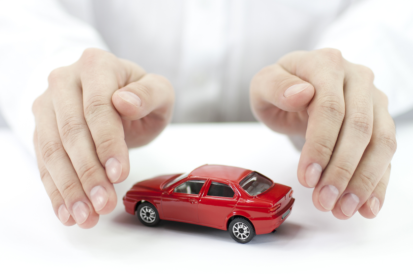car insurance - protecting a toy car with hands