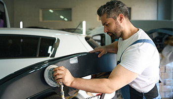 tech at auto body shop buffing car part