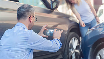 male taking photo of car accident for proof of uninsured motorist coverage