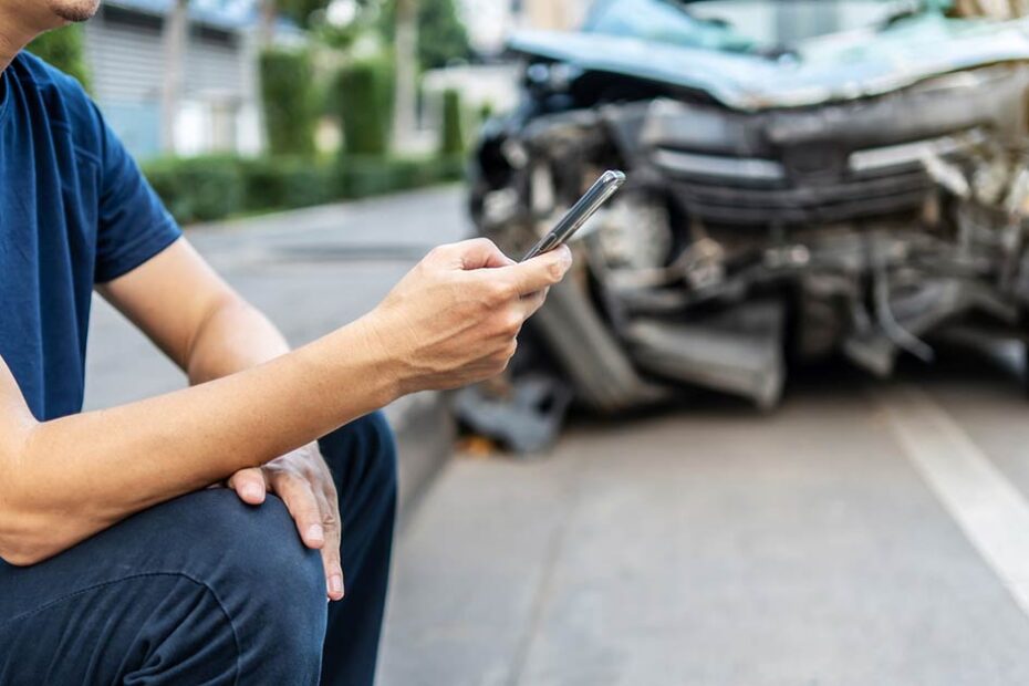 male driver checking phone if he has gap insurance after a car accident