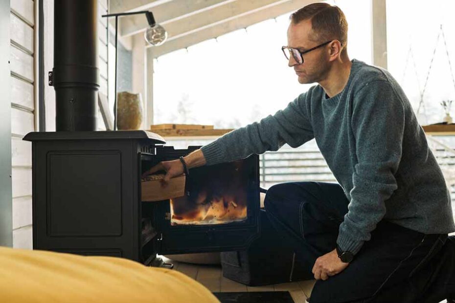 man winterizing home by adding wood in fireplace