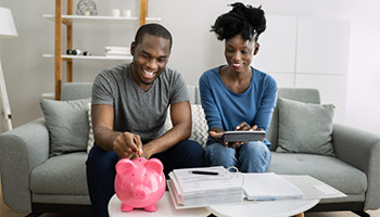 Couple saving money for a down payment. Putting money into a piggy bank. 