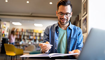 Student studying for class. Student is at a desk looking at a notebook. An example of a good student auto insurance discount. 