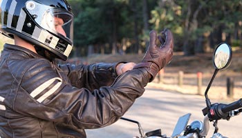 Motorcycle rider putting on safety gear and leather gloves. 