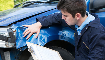 Repair shop employee reviewing a car's damage to determine quote. 