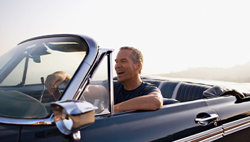 Man driving down the highway in a convertible car.