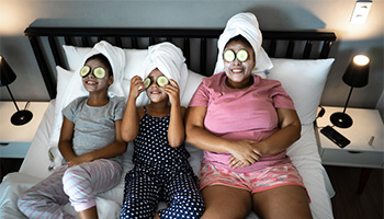a mother with her children on their staycation with cucumber over their eyes and face masks.
