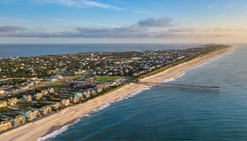 Arial view of the Outer Banks in North Carolina. There is a pier and a large row of houses.