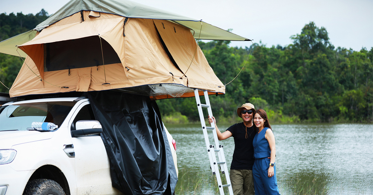 Two people standing in front of an open rooftop tent