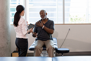 physical therapist helping male with shoulder pain