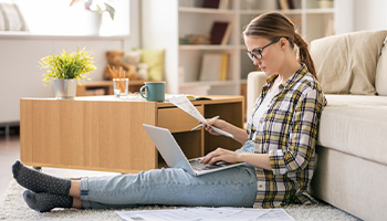 person sitting on the floor working on a travel budget for their trip abroad