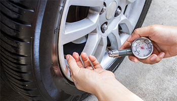 A person checking their tire pressure to help improve their gas mileage.