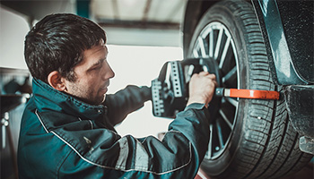 A mechanic putting a tire alignment tool onto a wheel to help gas mileage.