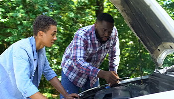 Father teaching his teenage driver basic car maintenance 
