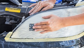 a person sanding their headlights