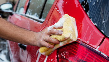 a person washing their red car