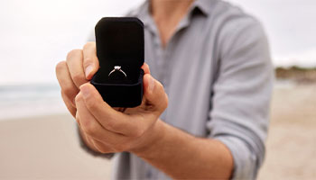 a person holding an engagement ring, which is something you'd purchase jewelry insurance for