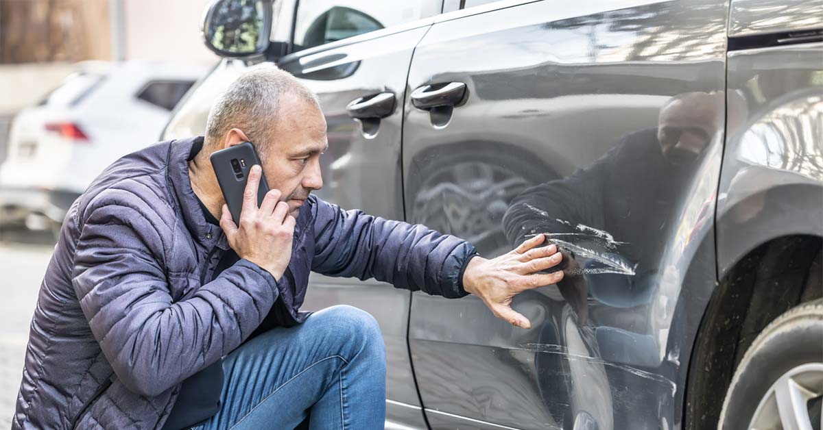 a person inspecting a car crash before filing an auto insurance claim