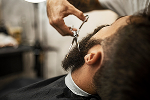 barber holding scissors near bearded man