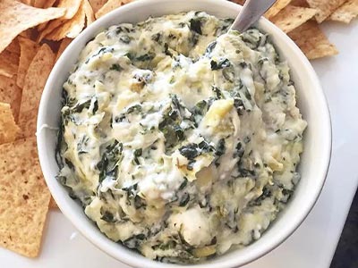 spinach artichoke cheese dip next to potato chips