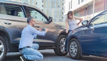 two people involved in an accident with each other. Person is taking a photo of the damage