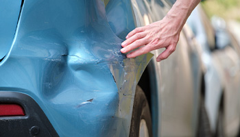 a person reviewing damage to their car after being in an accident