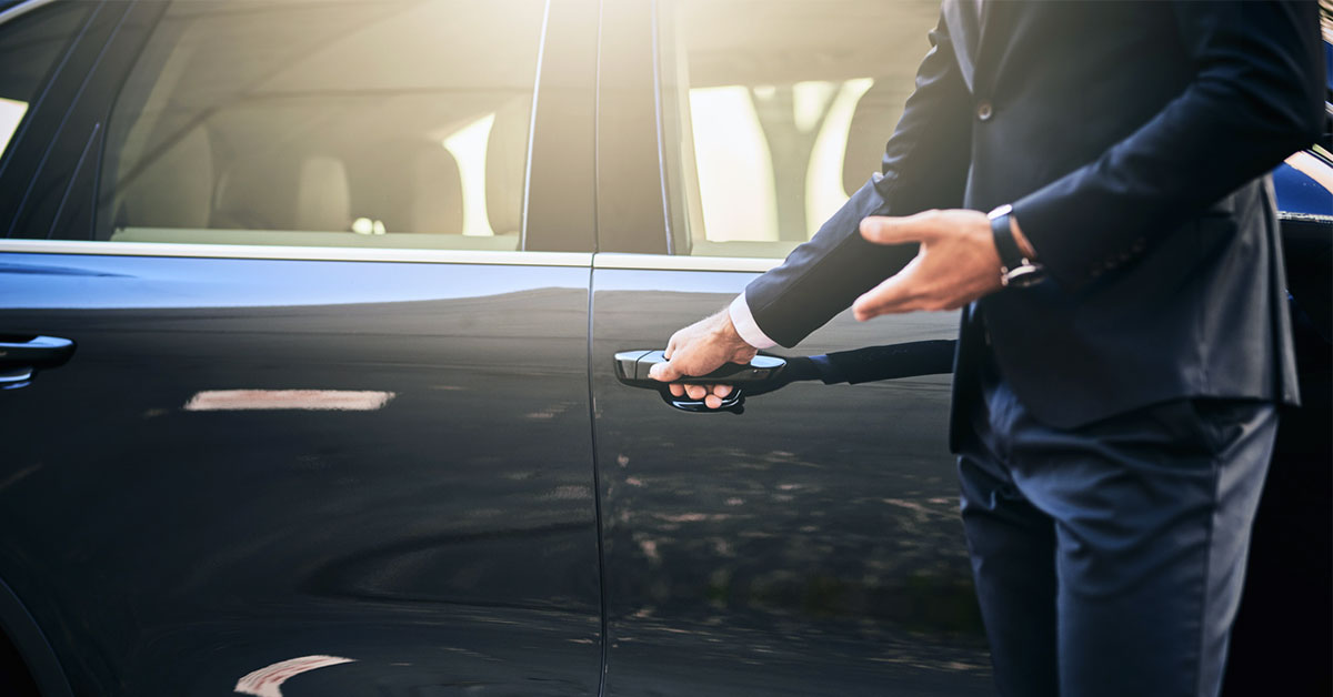 chauffeur offering to open luxury car door - livery service