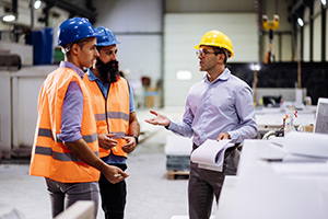 manager having conversation with two warehouse workers about workplace safety