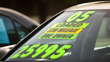 a used car for sale at a used car lot. Car is priced at $25,995 and has bright neon colors