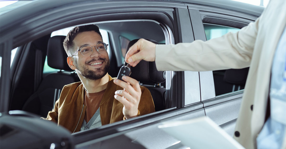 A person purchasing a car from the dealership and being handed the keys