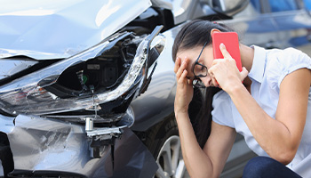 a person on the phone next to their damaged car