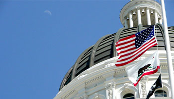 California's capital building with its flag and the US flag