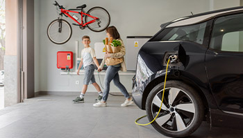 a family leaving their electric car to charge at home in the garage