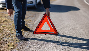 a person setting up a traffic hazard triangle
