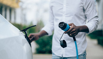 person plugging in an electric vehicle to charge