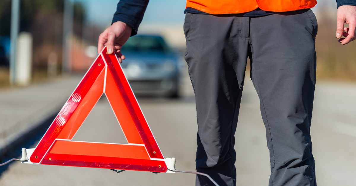 man installing a traffic hazard triangle