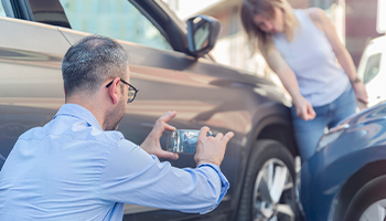 person taking photo of car accident damage.