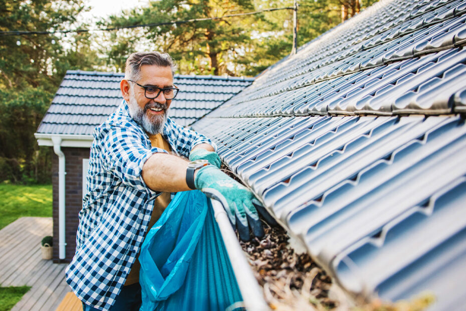 man clearing home gutters preparing for fall