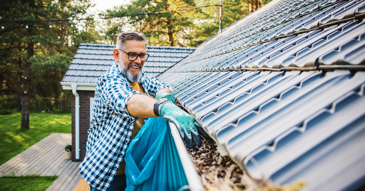 man clearing home gutters preparing for fall