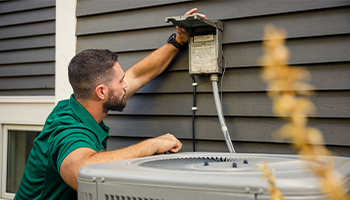 A home protection plan service provider taking a look at an outdoor panel for home appliance repair diagosis
