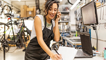 bicycle mechanic working in a shop talking on phone to gather certificate of insurance
