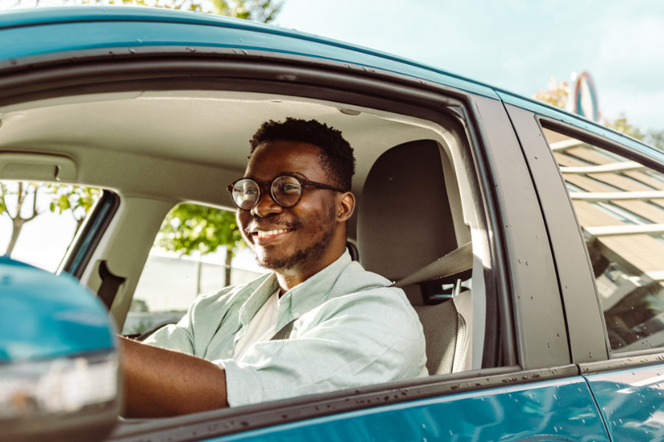 young adult teen driver with car insurance driving a blue car on a sunny day