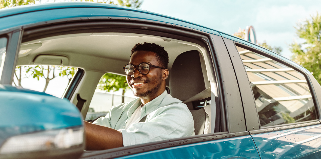 young adult teen driver with car insurance driving a blue car on a sunny day