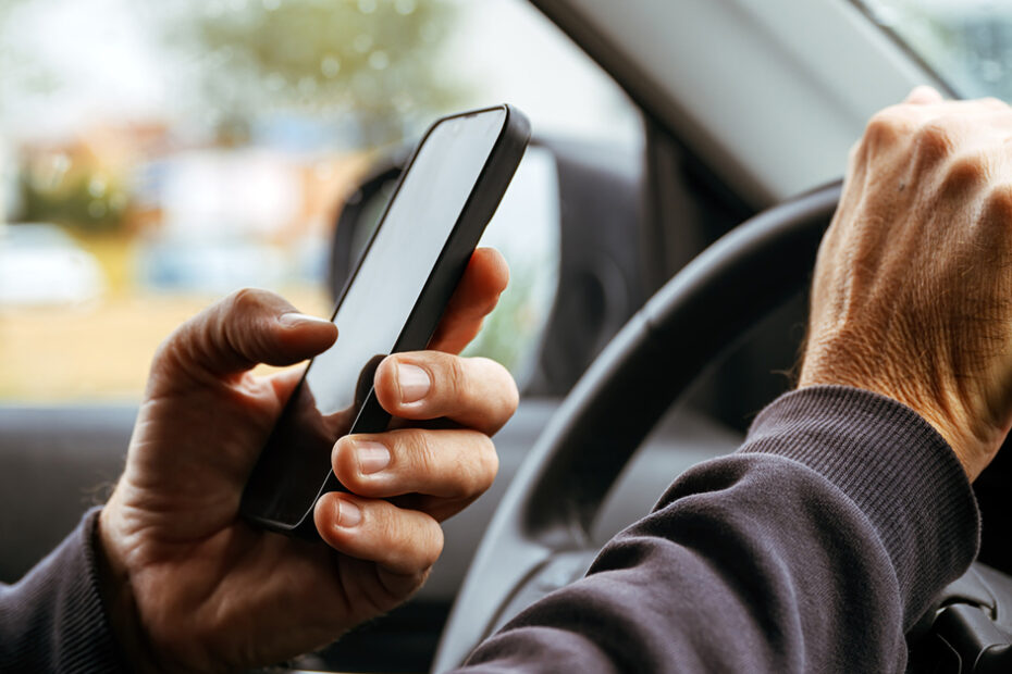 a distracted person driving using their phone at the wheel