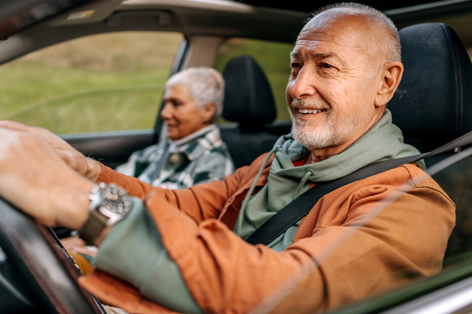 senior couple in a car driving down the road and they have car insurance