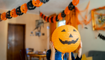 a person covering their face with a jack-o-lantern while decorating their home