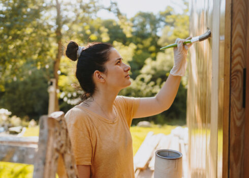 a person painting the exterior of a home wall